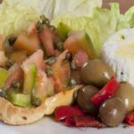 Caponata siciliana con melanzane, pomodori e olive, servita in un piatto tradizionale.