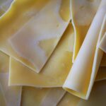 Sfoglia fatta in casa per lasagne, con impasto steso e pronto per essere tagliato.