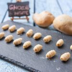 Gnocchi di patate freschi su un piano di lavoro con farina e ingredienti.