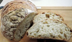 Pane casereccio a lievitazione naturale appena sfornato, crosta dorata e alveolatura perfetta.