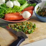 Pentola con brodo di carne in cottura, ingredienti freschi sul tavolo, ricetta della nonna.