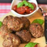Polpette italiane dorate su un piatto, accompagnate da salsa di pomodoro e basilico fresco.