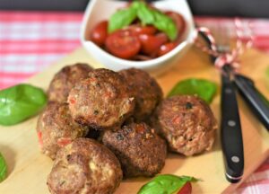 Polpette italiane dorate su un piatto, accompagnate da salsa di pomodoro e basilico fresco.