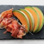 Fetta di melone con prosciutto su un piatto, un abbinamento fresco e gustoso per la cena.