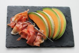 Fetta di melone con prosciutto su un piatto, un abbinamento fresco e gustoso per la cena.