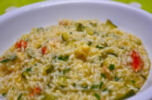 Risotto alla milanese cremoso, con zafferano e guarnizione di parmigiano, servito in un piatto bianco.