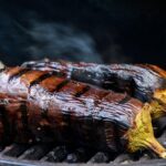 Melanzane grigliate con spezie su griglia, pronte per essere servite.