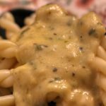 Pasta e fagioli cremosa in una ciotola, con guarnizioni di erbe fresche.